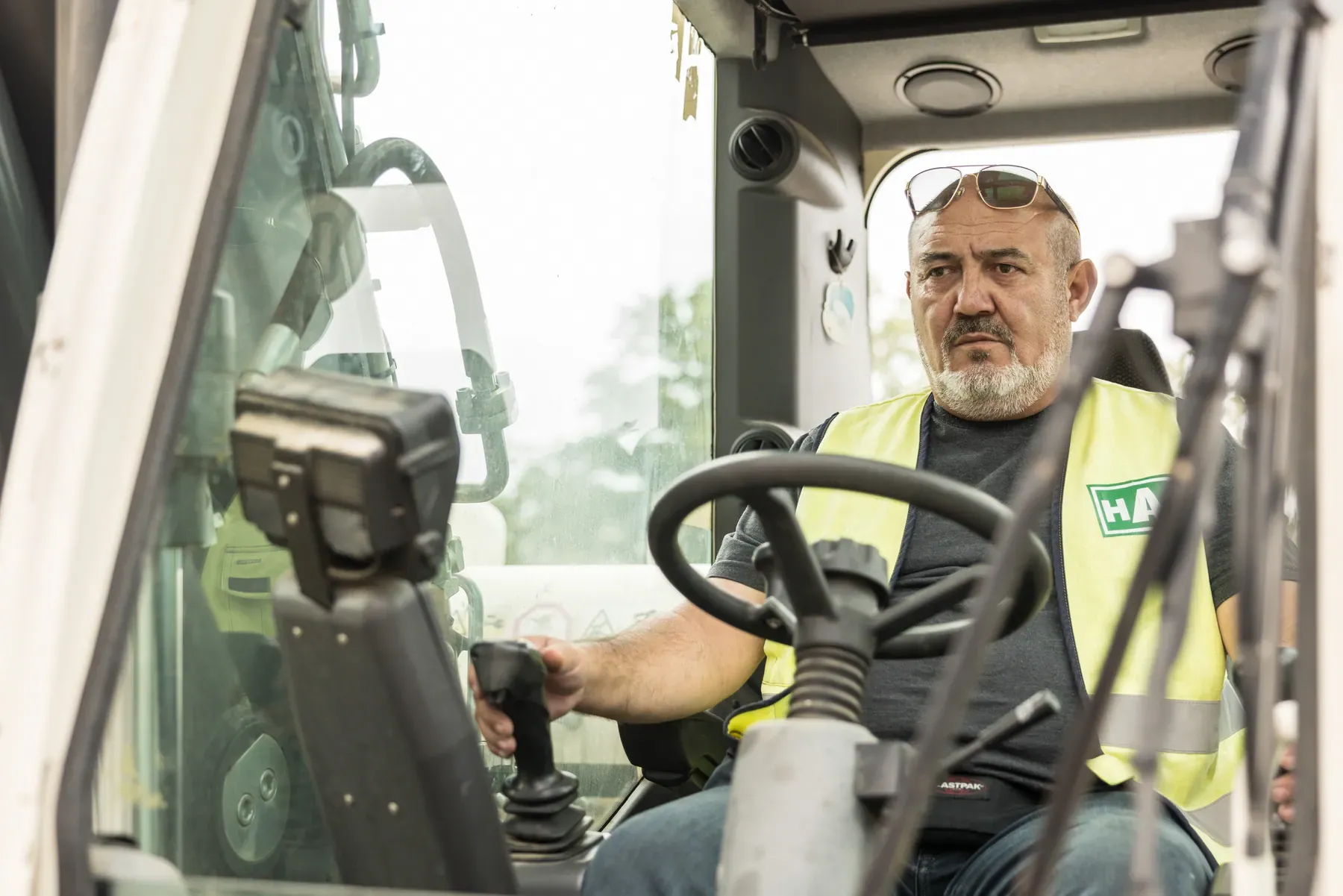 HAN-Baggerfahrer in Warnweste in der Kabine eines Mobilbaggers