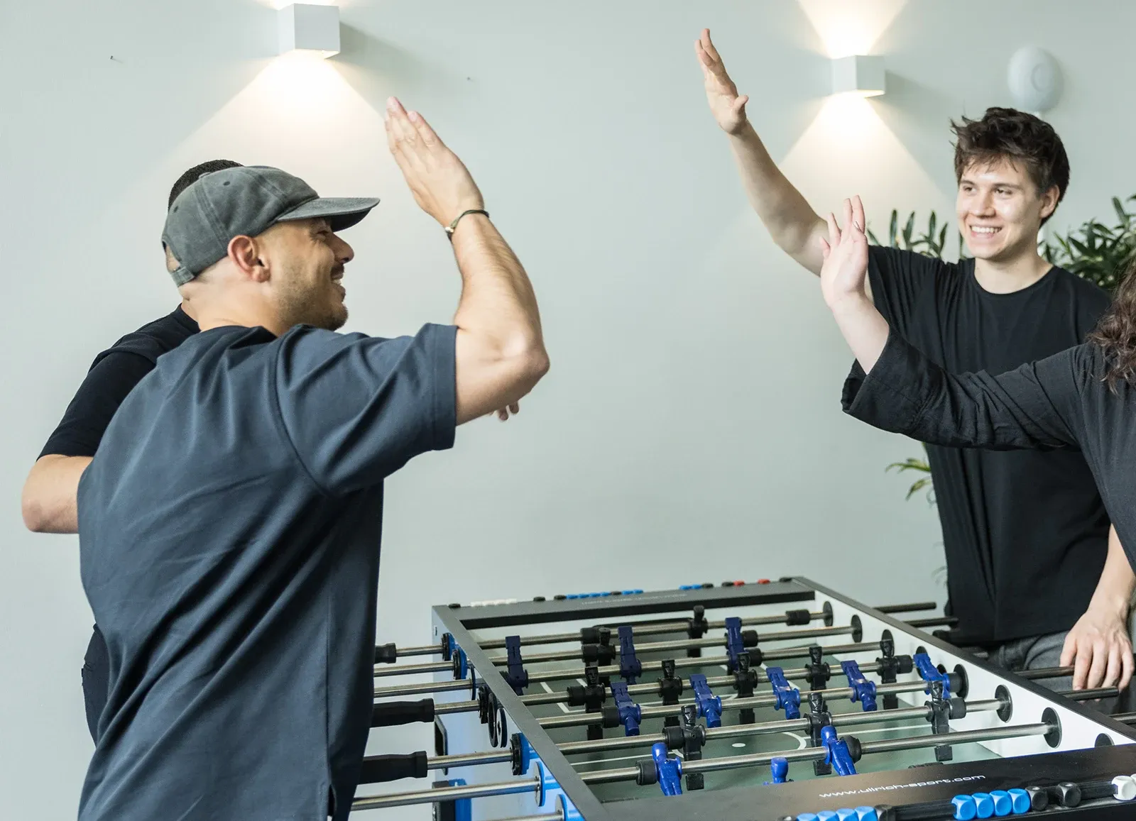Zwei junge HAN-Kollegen klatschen sich am Kickertisch ab