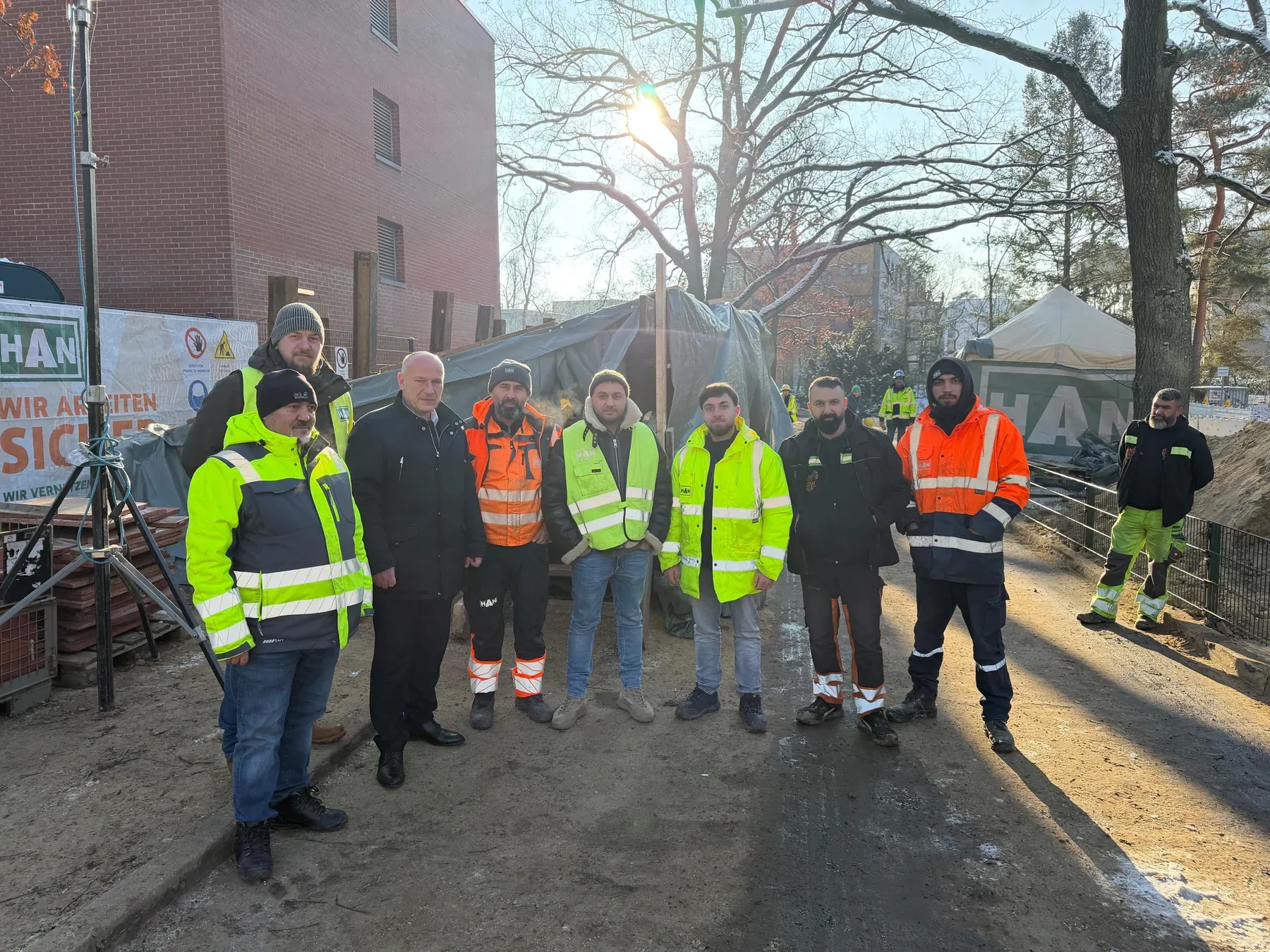 HAN-Team in Warnkleidung an der Einsatzstelle, im Hintergrund HAN-Bauzaunbanner und Zelte, Winterlicht